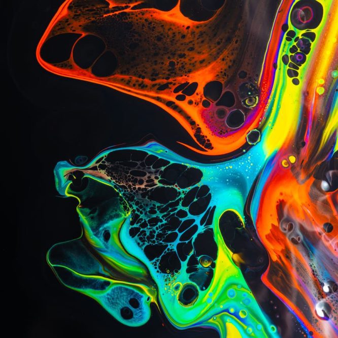 colorful mix of neon paints swirling on black surface